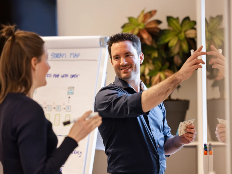 Coach in Lean Six Sigma die een deelnemer begeleidt bij het oplossen van een vraagstuk tijdens praktijkcertificering