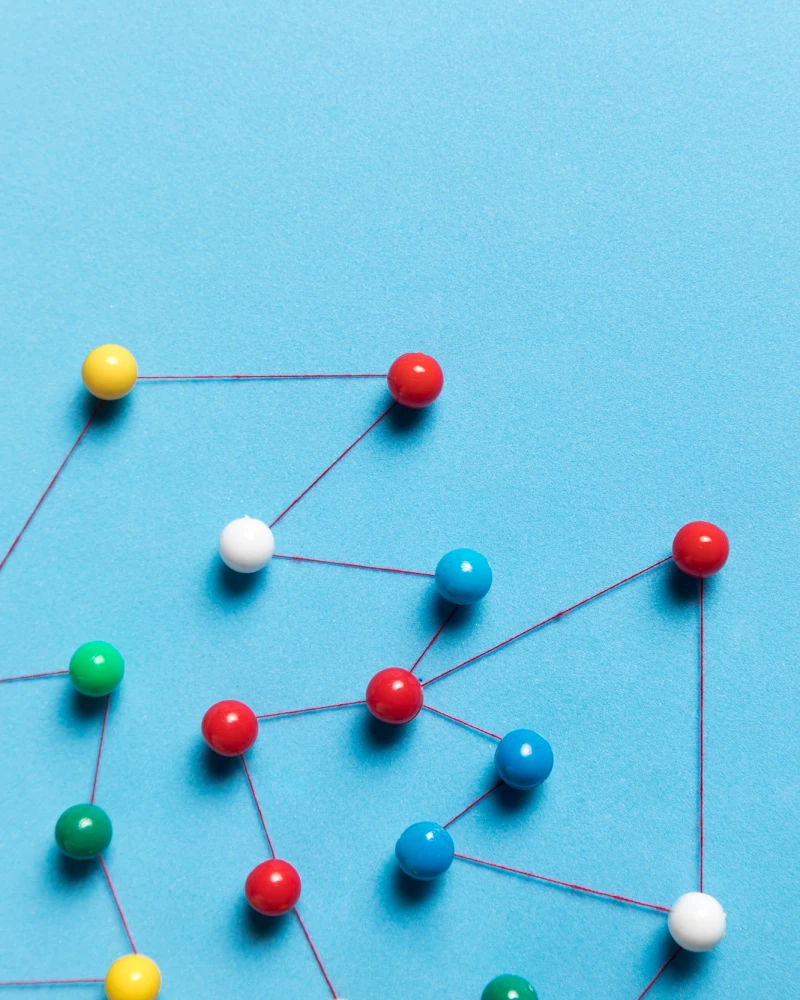 Gekleurde prikspelden met lijnen daartussen als symbool voor verbinding van teams in de Obeya
