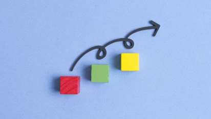 Continu verbeteren met Lean Six Sigma in kleine stapjes uitgelegd met drie houten blokjes met daarboven een pijl met krullen