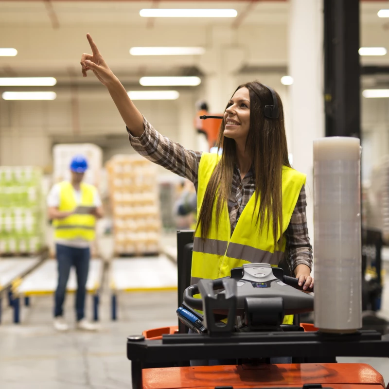 Vrouw op een forkheftruck in sector Logistiek, die hulp krijgt van een consultant in Lean Six Sigma en Continu Verbeteren