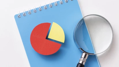 Notitieblok met een loep daarop die op abstracte wijze aangeeft dat er criteria zijn voor Lean Six Sigma praktijkcertificeringen van Impactery