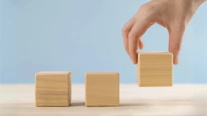 Een hand die een houten blokje plaatst als metafoor om flow te verbeteren