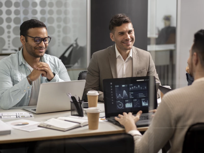 Mensen die met laptops op tafel een bespreking hebben, typerend voor de sector IT en Technologie