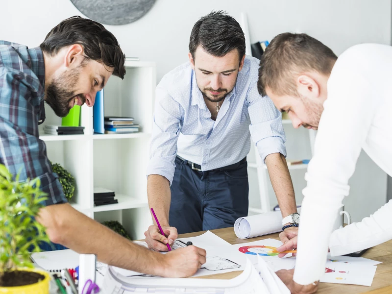 Drie mannen met papieren op tafel tijdens het inrichten van visueel management op de werkvloer.