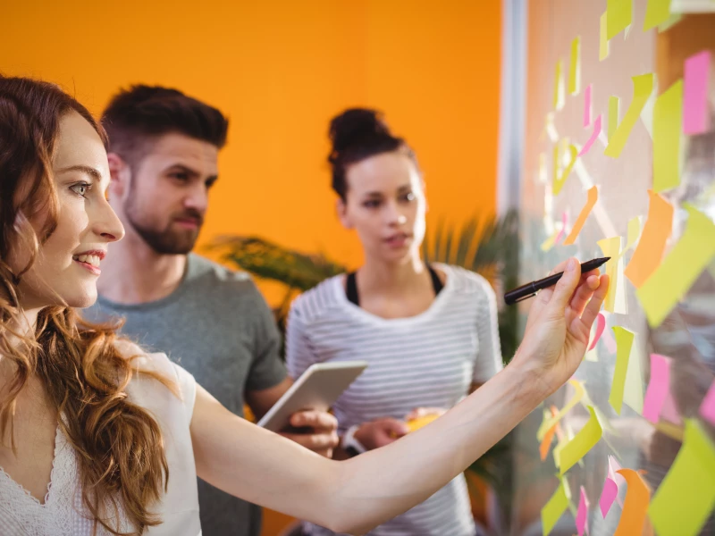 Een groep collega's die post-its schrijven om samen mogelijke oorzaken te verkennen