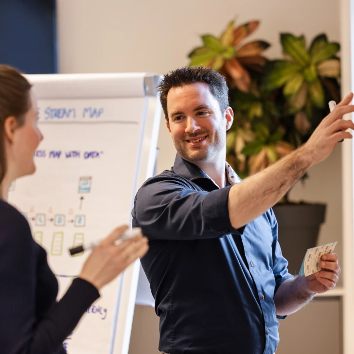 Consultant en Trainer wijst naar whiteboard tijdens interactieve Lean Six Sigma sessie
