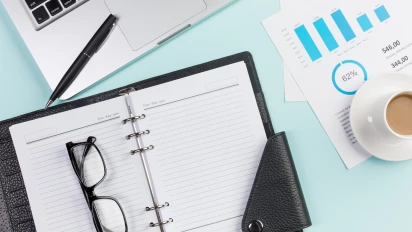 Laptop, notitieblok, grafieken en koffie als standaard elementen die horen bij project management