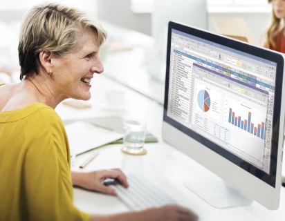 Vrouw die lachend achter een computer zit en daarop naar een dashboard kijkt, wat past bij de sector IT en Technologie