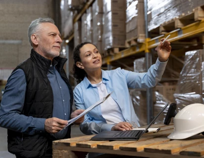 Man en vrouw in een magazijn met stellingkasten en dozen, passend bij sector Logistiek